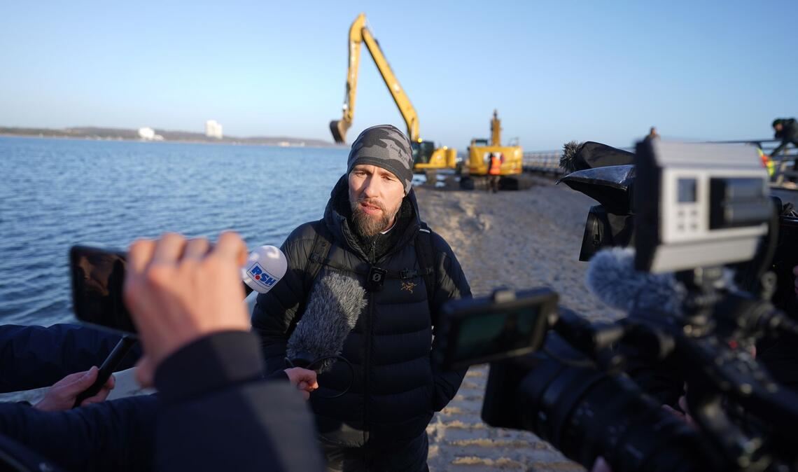 Robert Marc Lehmann spricht mit den Medien am Strand, in dessen Nähe der gestrandete Buckelwal im Wasser gelegen hatte.