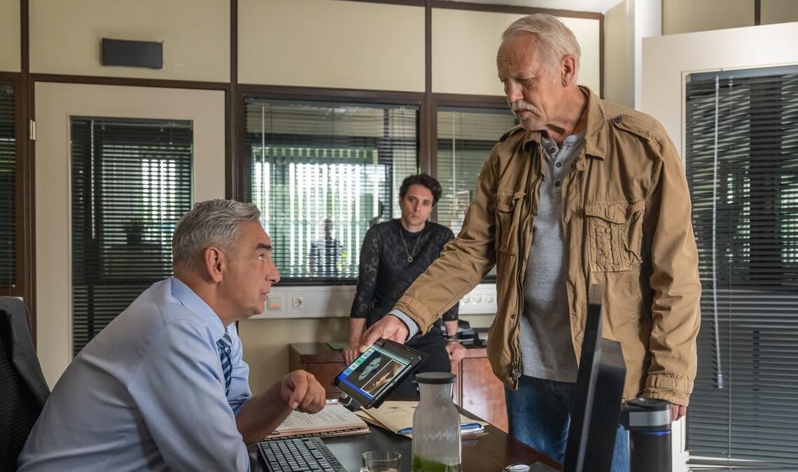 Rogov (re.) und Kollege Vincent Ross (André Kaczmarczyk, Mitte) informieren ihren Chef Karol Pawlak (Robert Gonera, li.) über den Stand der Dinge.