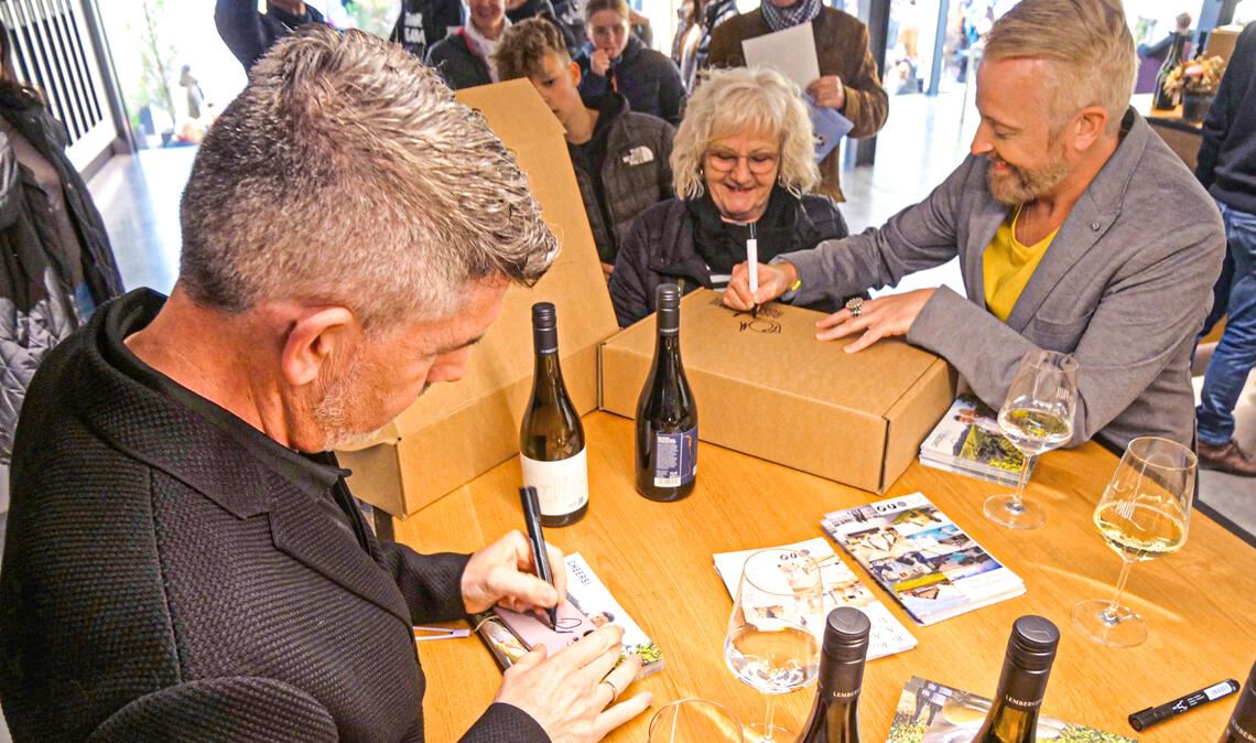 Run auf die Autogramme. Die beiden Sänger signieren Weinflaschen und -kartons. Fotos: Friedrich