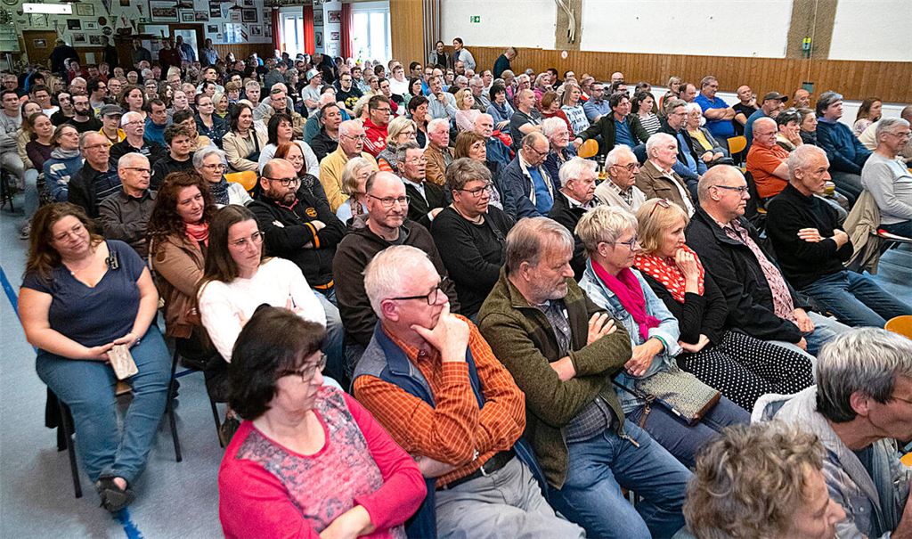 Rund 200 Besucher verfolgen die Bürgerversammlung in Großglattbach, bei der unter anderem Planungsamtsleiter Armin Dauner und Regionalverbandsdirektor Sascha Klein Stellung zum Thema Windkraft nehmen. Gegen die Pläne demonstriert Walter Müller. Fotos: Fotomoment (3)/Deeg