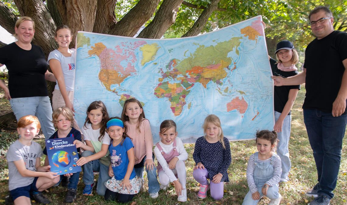 Sarah Elsäßer und Oliver Höhner übergeben im Rahmen des Kürbisfests als Spende des Fördervereins eine Weltkarte und Atlanten für die Mühlhäuser Grundschule. Foto: Fotomoment