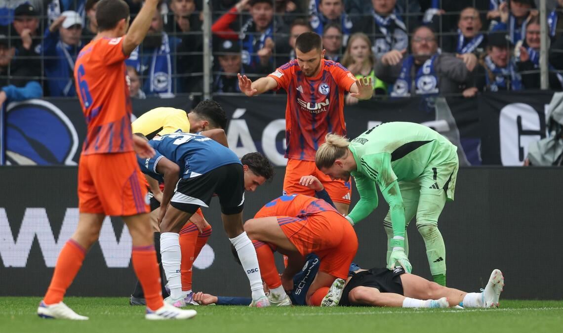 Schalke-Profi Nikola Katic hilft seinem am Boden liegenden Gegenspieler Joel Grodowski sofort.