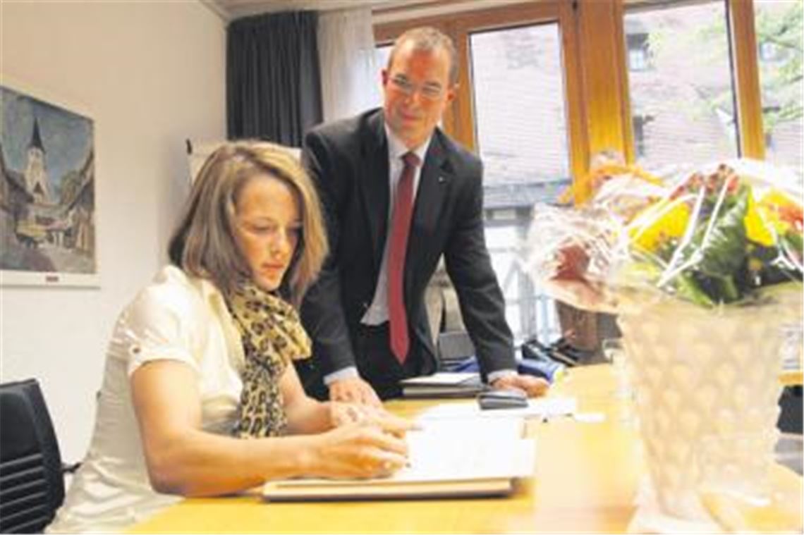 Schicke goldene Bluse passend zum Anlass: Im kleinen Sitzungssaal des Mühlacker Rathauses verewigt sich Jaqueline Schellin unter den Augen von Oberbürgermeister Frank Schneider mit einem ihrer Lebensmottos im Goldenen Buch der Stadt.
Foto: Eigner