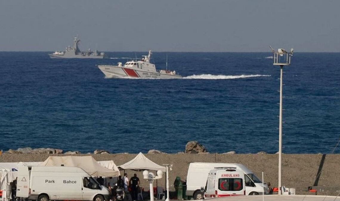 Schiffe fahren in der Nähe des Hafens von Kyrenia vorbei, während im türkisch besetzten Norden Zyperns ein Krankenwagen am Ufer geparkt ist, nachdem vor der Nordküste der Insel eine Passagierfähre gekentert war.