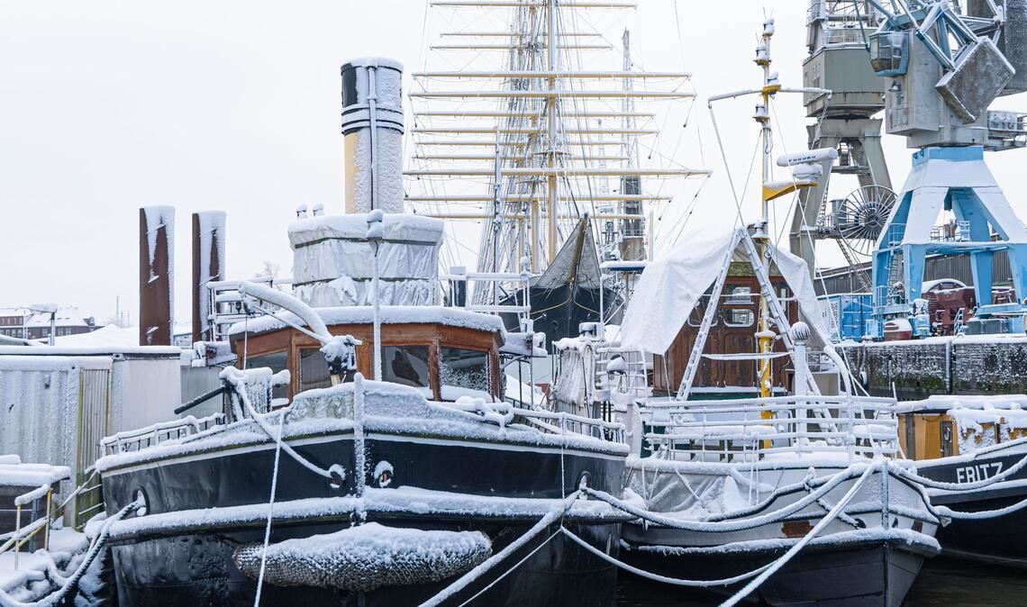 Schneebedeckte Schiffe liegen im Museumshafen in Hamburg.