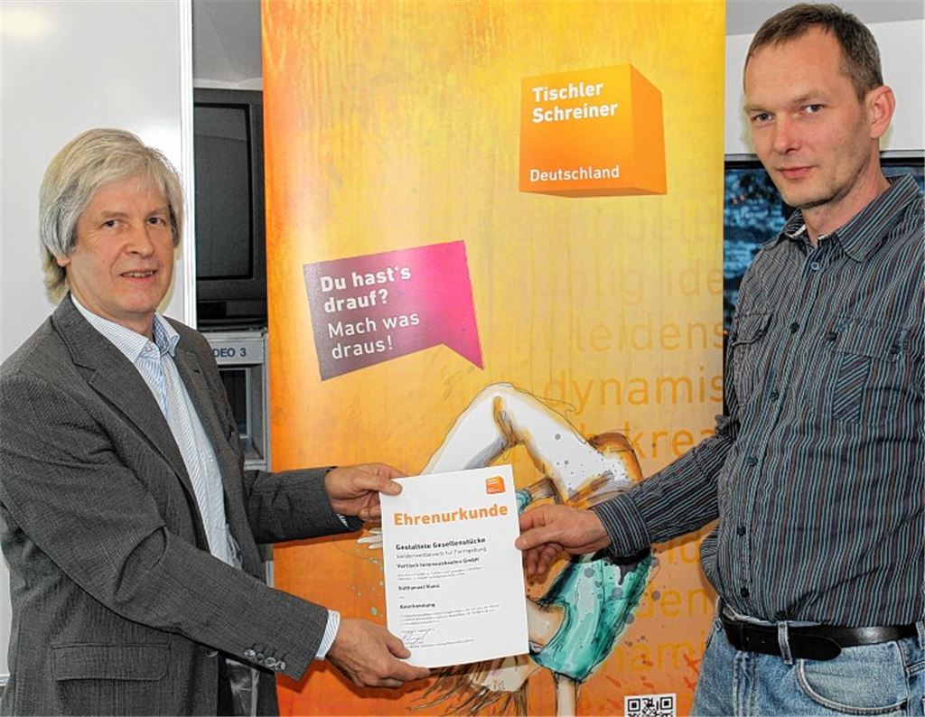 Schreinerobermeister Reinhard Engel (li.) überreicht seinem Meisterkollegen Thomas Quitschke (Vortisch GmbH) eine Urkunde für besondere Ausbildungsleistungen.