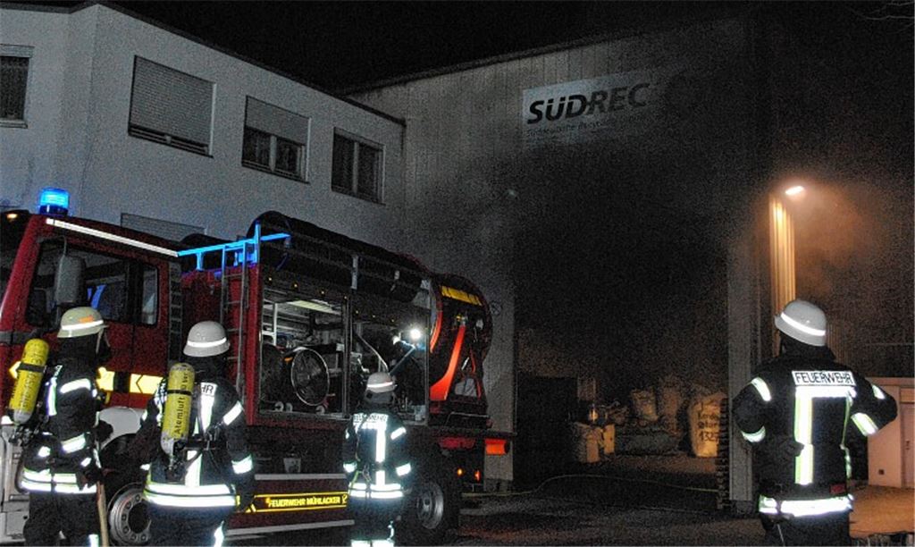 Schwarzer Rauch dringt aus der Firmenhalle, in der am Freitagabend ein Feuer ausgebrochen ist. Der Großlüfter kommt zum Einsatz.