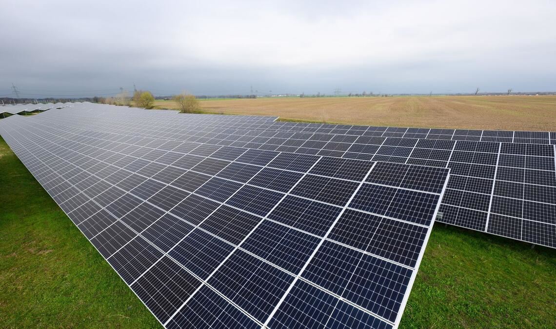 Solaranlagen sind für ein Photovoltaik-Speicher-Kraftwerk auf einer Wiese montiert.