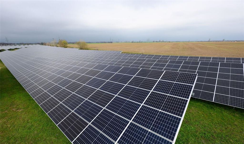 Solaranlagen sind für ein Photovoltaik-Speicher-Kraftwerk auf einer Wiese montiert.