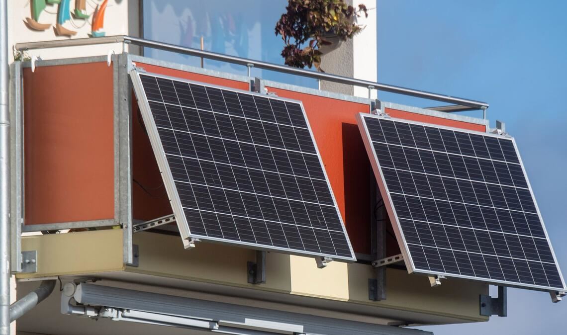 Solarmodule für ein sogenanntes Balkonkraftwerk hängen an einem Balkon.