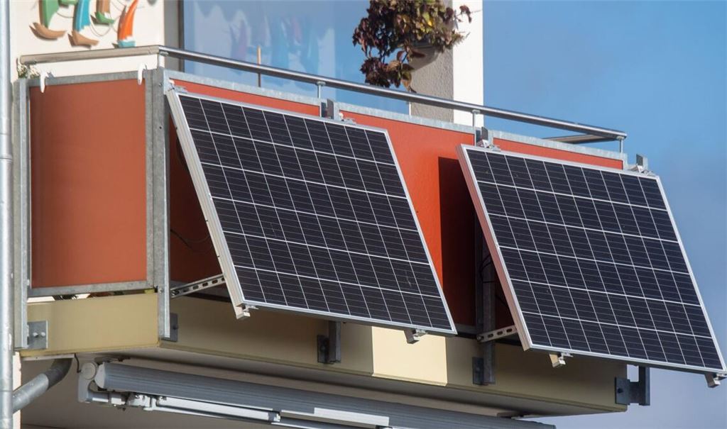 Solarmodule für ein sogenanntes Balkonkraftwerk hängen an einem Balkon.