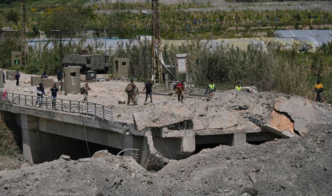 Soldaten und Zivilisten überqueren eine zerstörte Brücke, die bei einem israelischen Luftangriff nahe der Küstenstadt Tyrus im Libanon getroffen wurde.