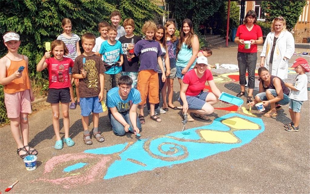 Sozialarbeiterin Stefanie Schneider (kniend), Christiane Sauter-Pflomm (4.v.re.) sowie Eltern und Schüler treten als Maler in Aktion. 