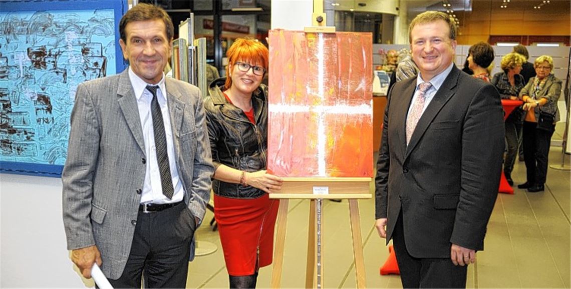 Sparkassen-Marktdirektor Gerd Owczarek (re.) und der ehemalige Kunstlehrer Rainer Zundel eröffnen die Ausstellung „Farbenspiele auf Leinwänden“ von Helga Aichele (Mitte). Foto: Fotomoment