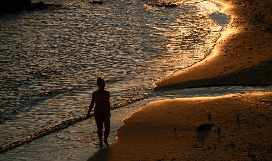 Spaziergang in der Abendsonne: Eine Person geht über den Sand am Milk Beach.