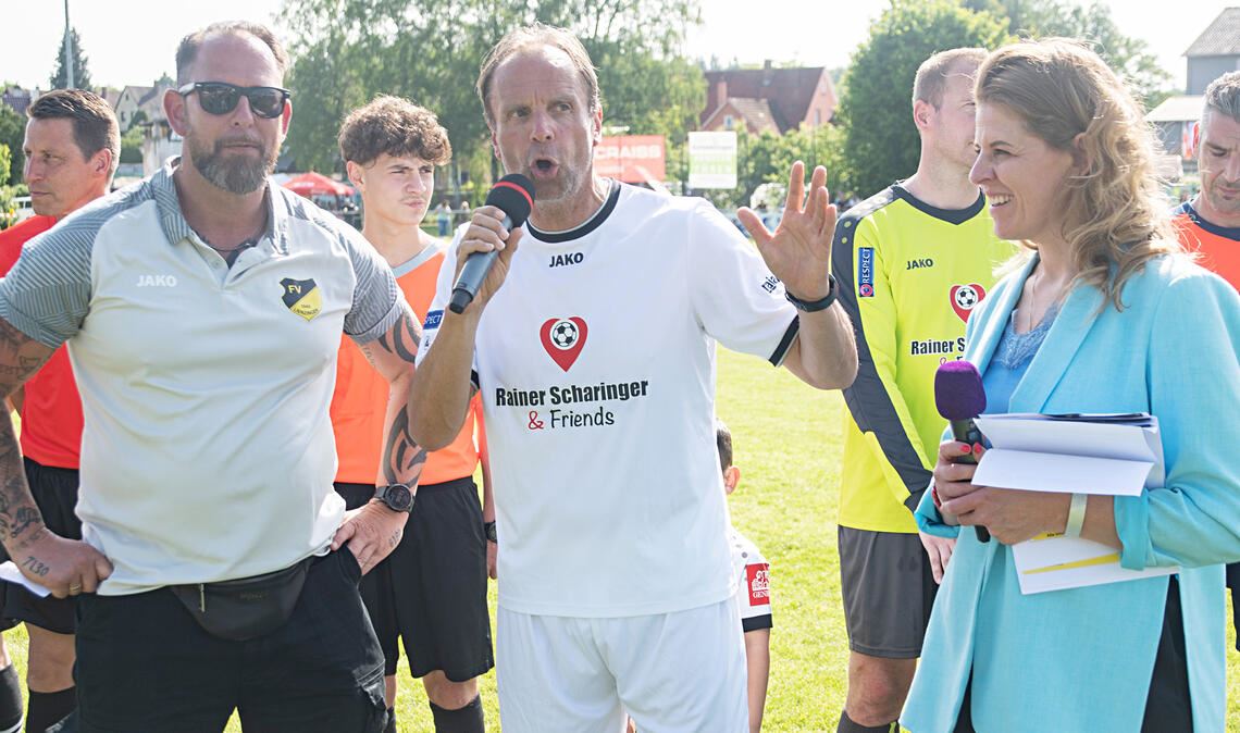 Sportvorstand sowie Organisator Michael Horntrich vom FV Lienzingen (links) und Moderatorin Claudia Wandrey rahmen Rainer Scharinger (Mitte) ein. Foto: Fotomoment