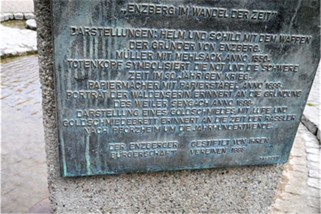 Stadtrat Theo Bellon (unten) zeigt die Skulptur „Enzberg im Wandel der Zeit“ auf dem Rathausplatz im Mühlacker Stadtteil. Foto: privat