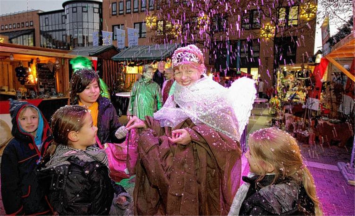 Stimmungsvolle Momente im Herzen der Stadt: Ein Schokoladenengel bringt Süßes unter das junge Volk, während eine kleine Schneekanone für winterliche Atmosphäre sorgt. 