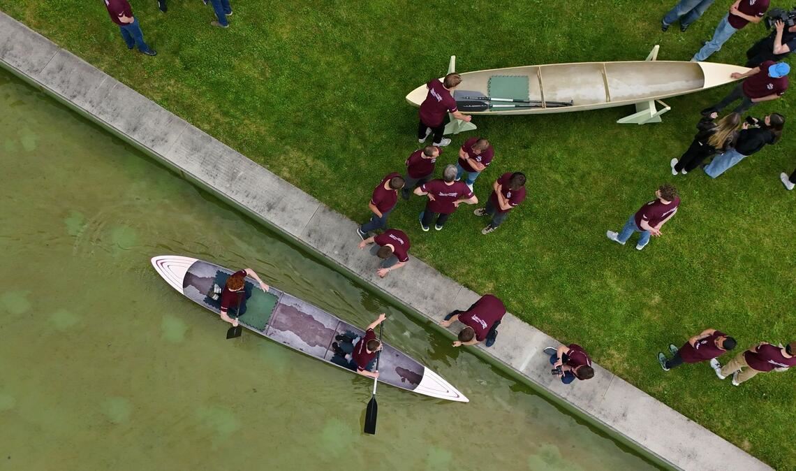 Studenten und Studentinnen der Bauhaus-Universität Weimar fahren mit dem Betonkanu auf dem Wasser im Weimarer Schwanseebad. (Aufnahme mit einer Drohne)