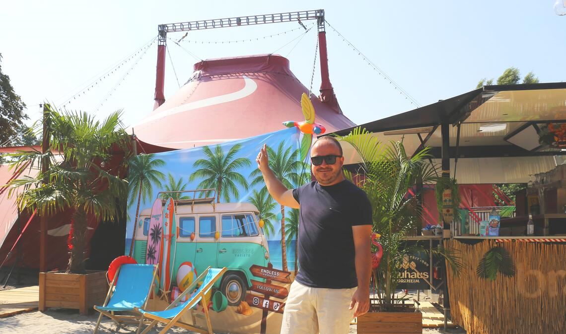 „Summer Trip“-Veranstalter Kevin Leppin zeigt das sommerlich gestaltete Zirkuszelt auf dem Festplatz im Letten in Mühlacker. Fotos: Schüller/Fotomoment