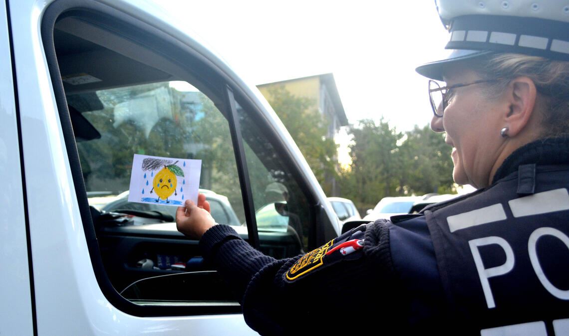Szene einer Aktion zum Start ins neue Schuljahr: Banu Kalay von der Verkehrsunfallprävention des Polizeipräsidiums Pforzheim verteilt an der Schiller-Grundschule „saure Zitronen“ an Eltern, die sich als Chauffeure ihrer Kinder nicht an die Regeln halten. Foto: Stahlfeld