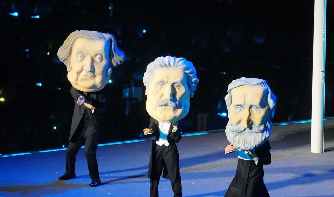 Tänzer tragen Masken der italienischen Komponisten Giuseppe Verdi, Giacomo Puccini and Gioachino Rossini während der Eröffnungsfeier unter dem Motto „Armonia“.