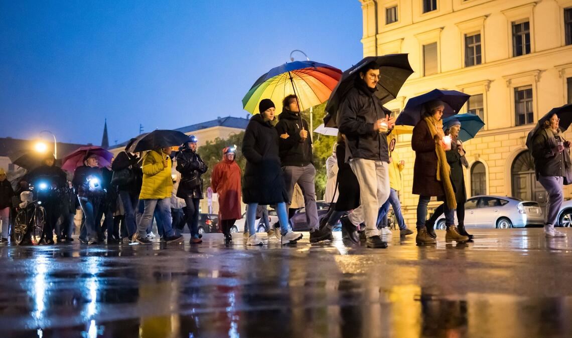 Teilnehmer des Schweigemarschs "Mach Dich auf für Menschlichkeit!" gehen mit Kerzen auf der Ludwigsstraße in München.