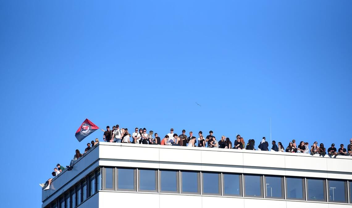 Teilnehmer stehen bei einer Demonstration mit dem Motto "Krieg und Krise haben System. Als Klasse vereint: Sozialismus erkämpfen!" auf dem Dach eines Hauses in Hamburg.