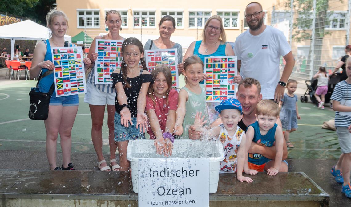 Tim Wumndschuh und Melanie Bischoff (hinten v. re.) feiern mit Kindern, Eltern und Lehrern beim Sommerfest an der Schule Enzberg eine „Reise um die Welt“. Foto: Fotomoment