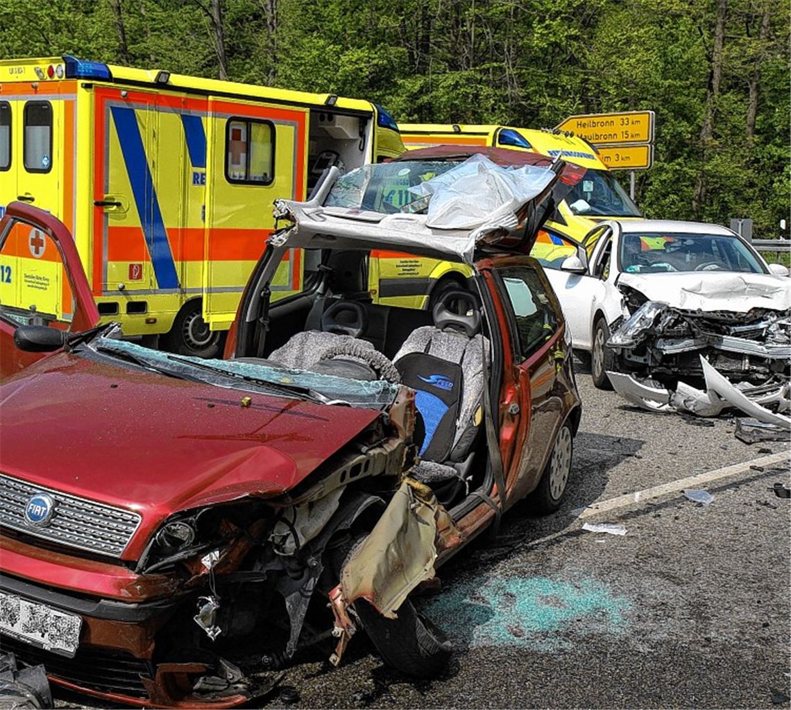 Totalschaden: Im Vordergrund der Wagen des 64-Jährigen, der in seinem Auto eingeklemmt wird und von der Feuerwehr, die das Dach öffnet, befreit werden muss.
