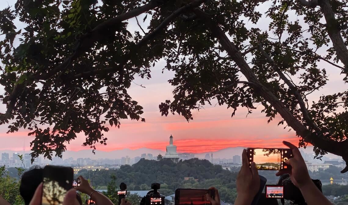 Bilder des Tages Touristen fotografieren mit ihren Handys den farbenfrohen Sonnenuntergang über der chinesischen Hauptstadt.