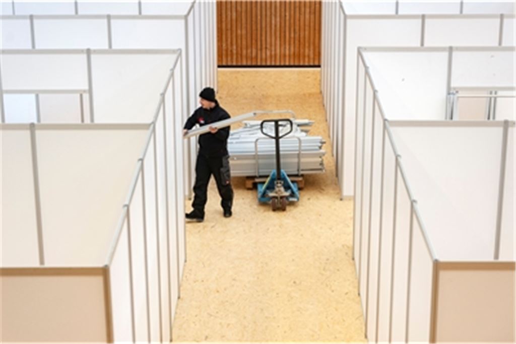 Trennwände schaffen Rückzugsräume für die Geflüchteten in der Mühlacker Sporthalle. Helfer von Bauhof, Feuerwehr und THW packen bei den Aufbauarbeiten mit an. Fotos: Fotomoment