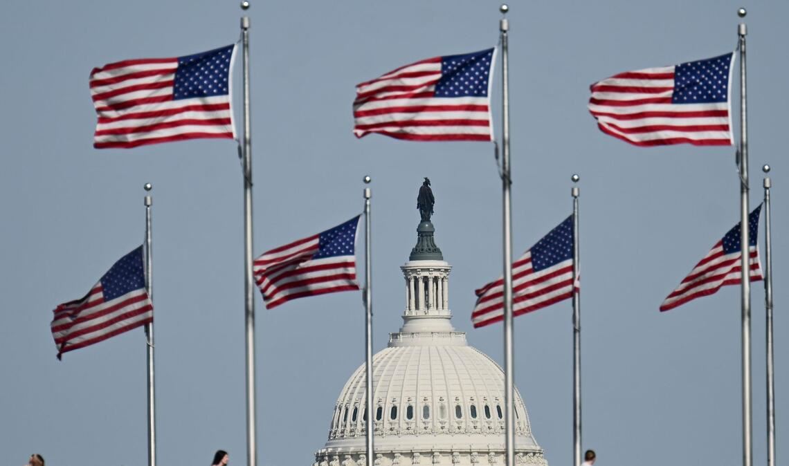 US-Fahnen wegen am Washington Monument. Im Hintergrund ist die Kuppel des US-Kapitols zu sehen.