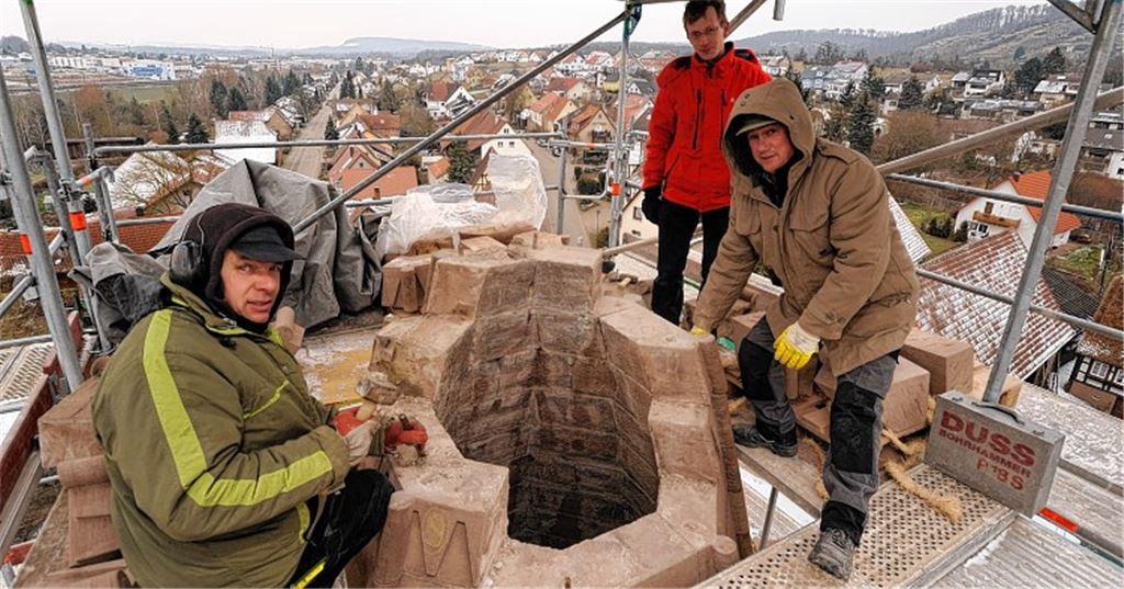 Über den Dächern von Schönenberg: Die Steinmetze Frank Sommerfeld (li.) und Josef Reisenhauer (re.) von der Firma Holz aus Eppingen erneuern den Sandstein-Aufbau an der Kirchturmspitze. Als schwindelfreier Beobachter verfolgt Pfarrer Markus Epting die Arbeiten.