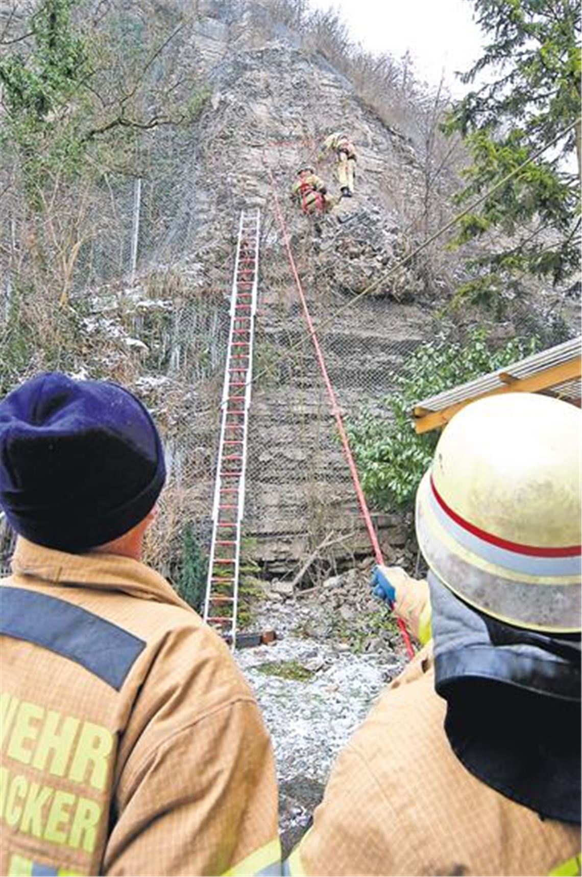 Ungewöhnlicher Einsatz in steilem Terrain: Die Mühlacker Feuerwehr seilt sich aus luftiger Höhe ab und sorgt dann für den kontrollierten Absturz loser Gesteinsbrocken, die sich im Sicherheitsnetz verfangen hatten, das die Anwohner der Enzstraße vor gefährlichem Steinschlag schützt. Foto: Kollros