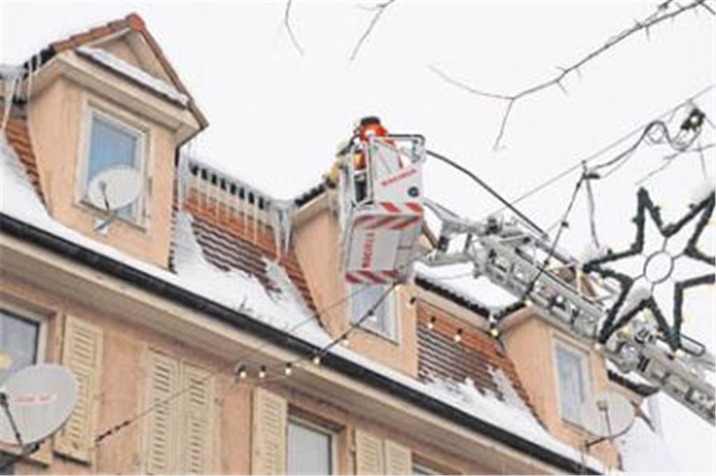 Unter Einsatz der Drehleiter beseitigen Feuerwehrleute zum Schutz der Fußgänger gefährliche Eiszapfen an Wohn- und Geschäftshäusern in Mühlacker. Foto: Franz