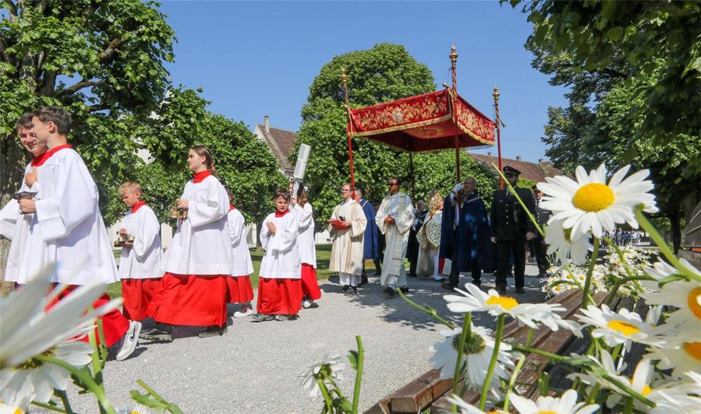 Unter einem Stoffbaldachin wird die Monstranz während der Fronleichnamsprozession am 8. Juni 2023 durch die Straßen des Dorfes Obermarchtal  getragen.