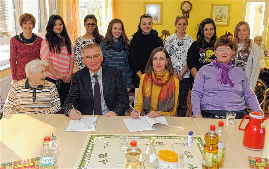 Ursula Günster und Andreas Petermann unterzeichnen im Beisein von Projektleiterin Ulrike Metzger und Schülerinnen (hinten v.li.) die Bildungskooperation.