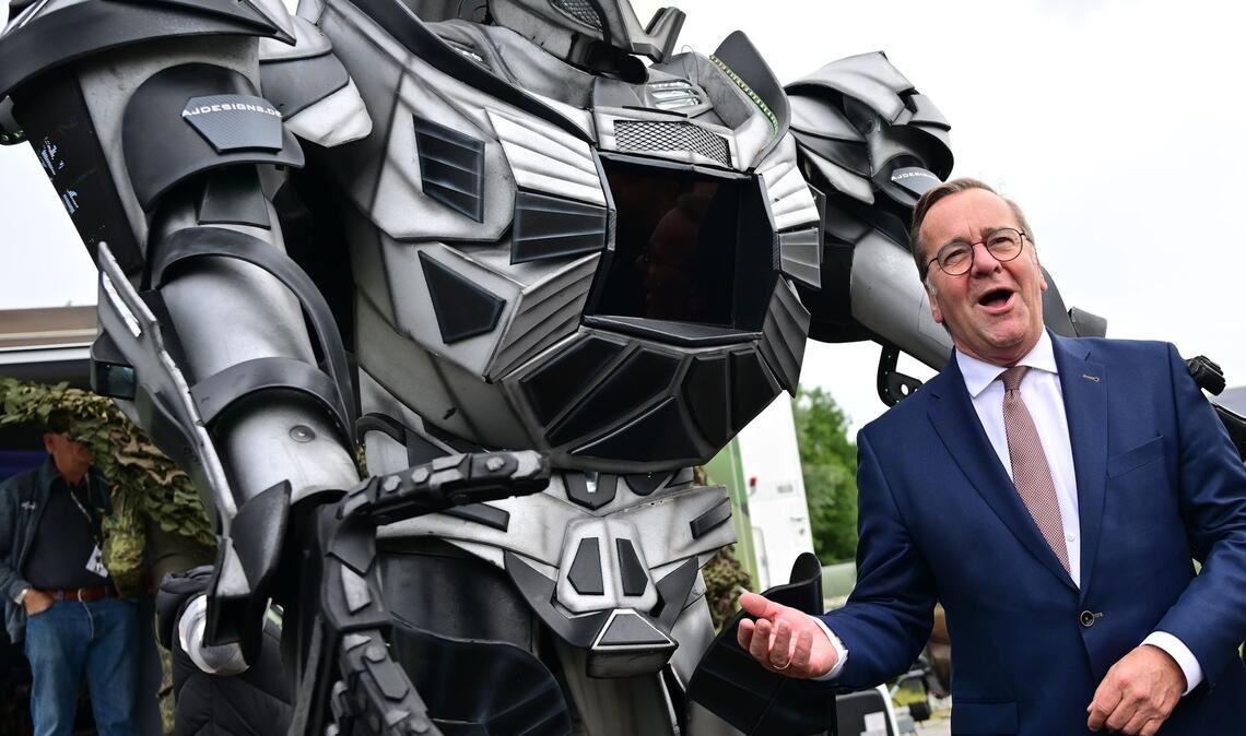 Verteidigungsminister Pistorius scherzt neben einer Transformer-Figur bei der ILA 2026 in Berlin.