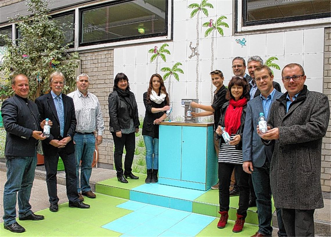 Vertreter von Schule, Stadt und Sponsoren nehmen mit den Schülersprechern Duygu Cetintas und Kay Kevin Schirner den neuen Trinkbrunnen in der Aula der Mörike-Schule in Betrieb.