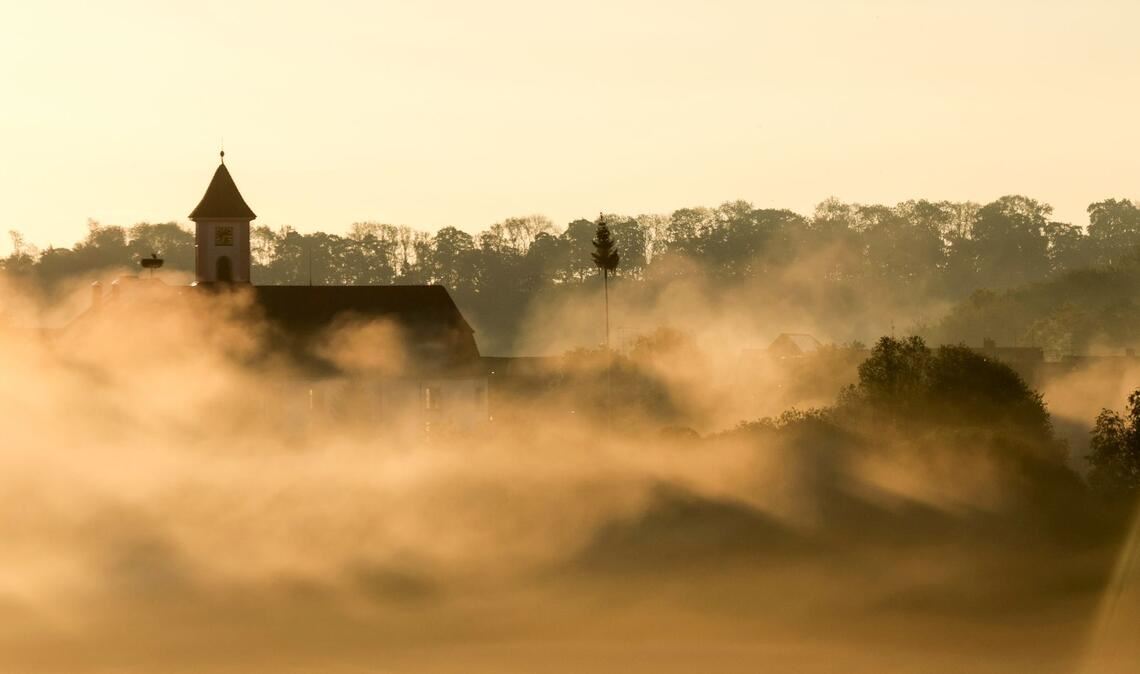 Vom Nebel umhüllt: die Kirche Sankt Gallus am Morgen kurz nach Sonnenaufgang.