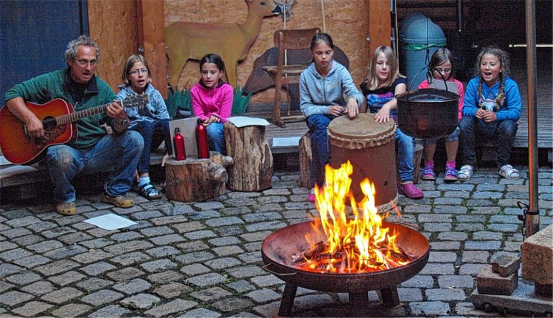 Von Büffeljagden singen die Kinder. Klemens Köberle begleitet sie mit der Gitarre, und Nancy und Lena geben an der Trommel den Takt vor. Foto: Filitz