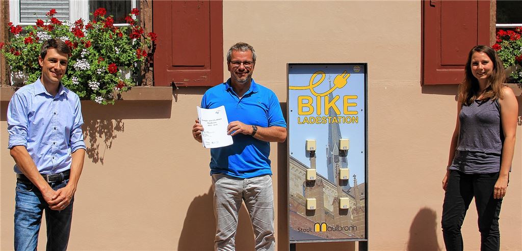 Vor der E-Bike-Ladestation am Rathaus: Übergabe der Energie- und CO2-Bilanz an Bürgermeister Andreas Felchle (Mitte) durch Björn Ehrismann, Leiter der Kommunalberatung des Energie- und Bauberatungszentrums Pforzheim/Enzkreis (ebz), und Klimaschutzmanagerin Lisa Andes.privat