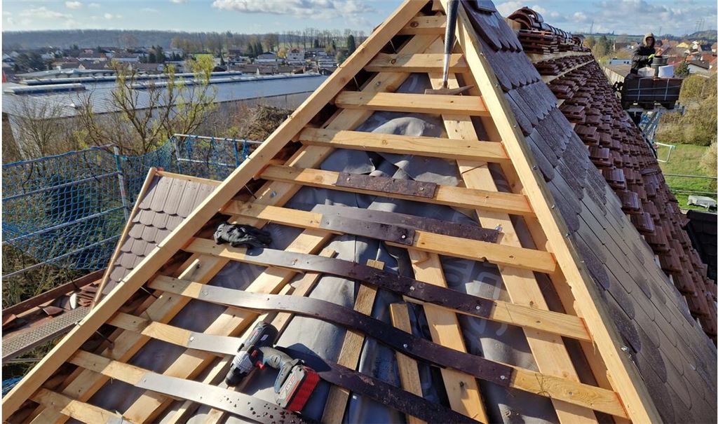 Vorbereitungen fürs „Ochsenauge“: Im Hintergrund schneidet Hannes, Mitarbeiter der Dachdeckerfirma Fink im zweiten Lehrjahr, die „Biberschwänze“ genannten Ziegel zu. Foto: privat