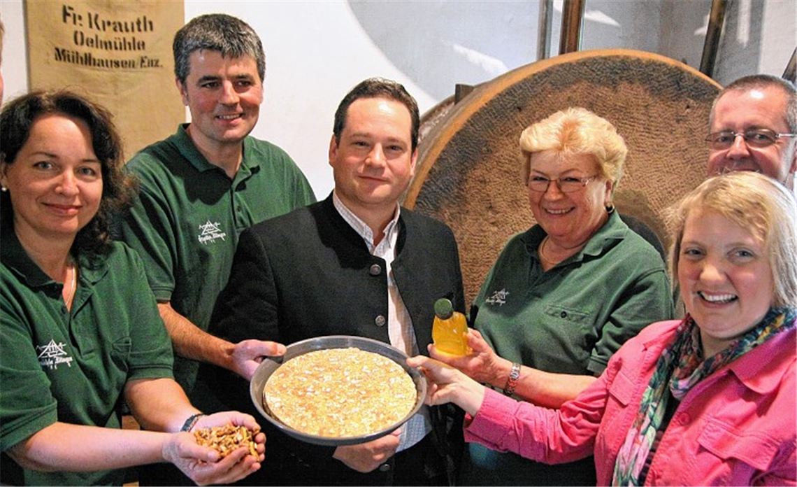 Während Cornelia Hofer-Krauth (li.) Walnusskerne in der Hand hält, zeigen Jürgen Krauth (2. v. li.) und seine Mutter Helga (3. v. re.) Minister Alexander Bonde (Mitte, der Bundestagsabgeordneten Katja Mast und Landrat-Vize Wolfgang Herz die Ölkuchen, die beim Pressen anfallen. Foto: Goertz