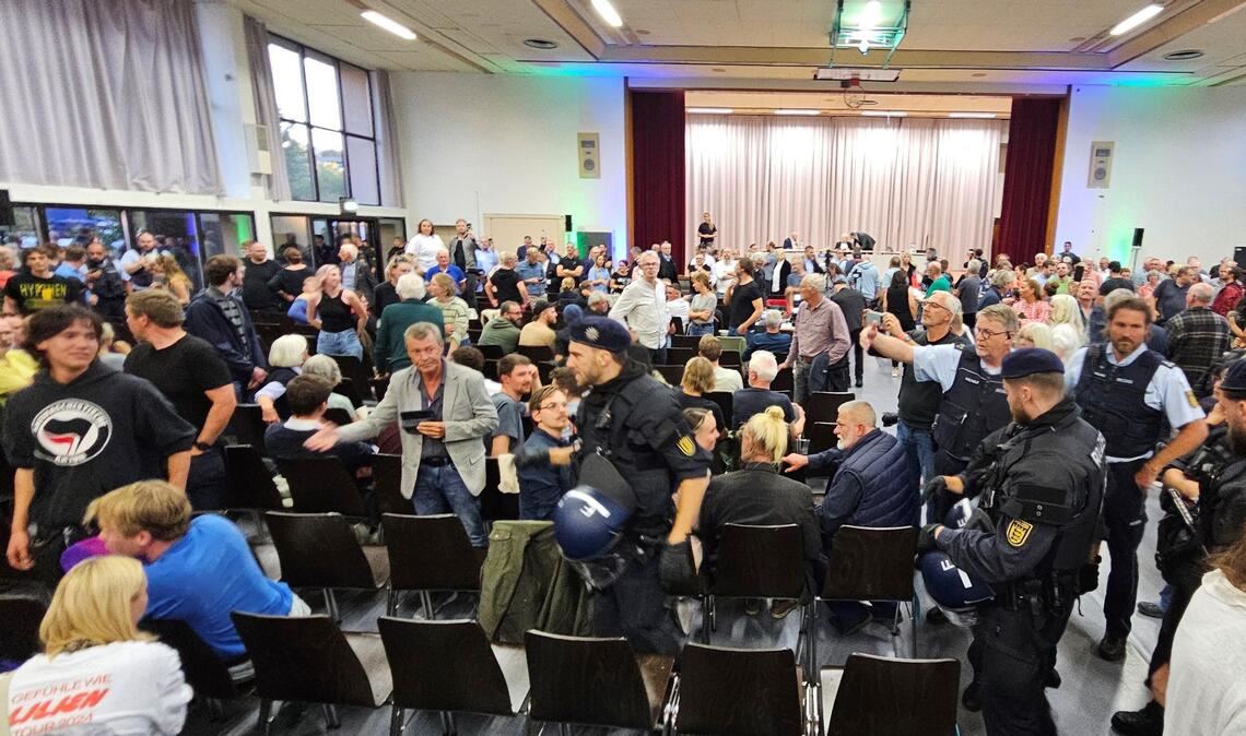 Während der Diskussion kommt es zu lautstarken Zwischenrufen, die Polizei schreitet ein.