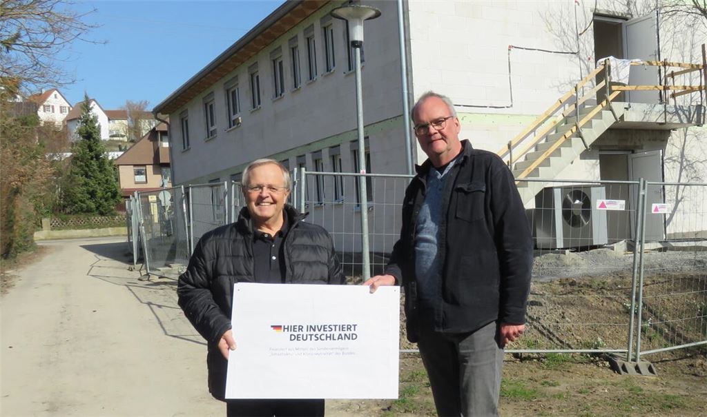 Werner Henle (li.) und Johannes Schulz freuen sich über Geld aus dem Sondervermögen. Noch ist das Schild, mit dem sie sich bedanken, selbst gebastelt. Eine größere Version wird bald an der Baustelle aufgestellt. Hier entsteht ein neues Obdachlosen- und Flüchtlingsheim. Ein Teil des bewilligten Geldes wird für das Projekt eingesetzt. Foto: Becker