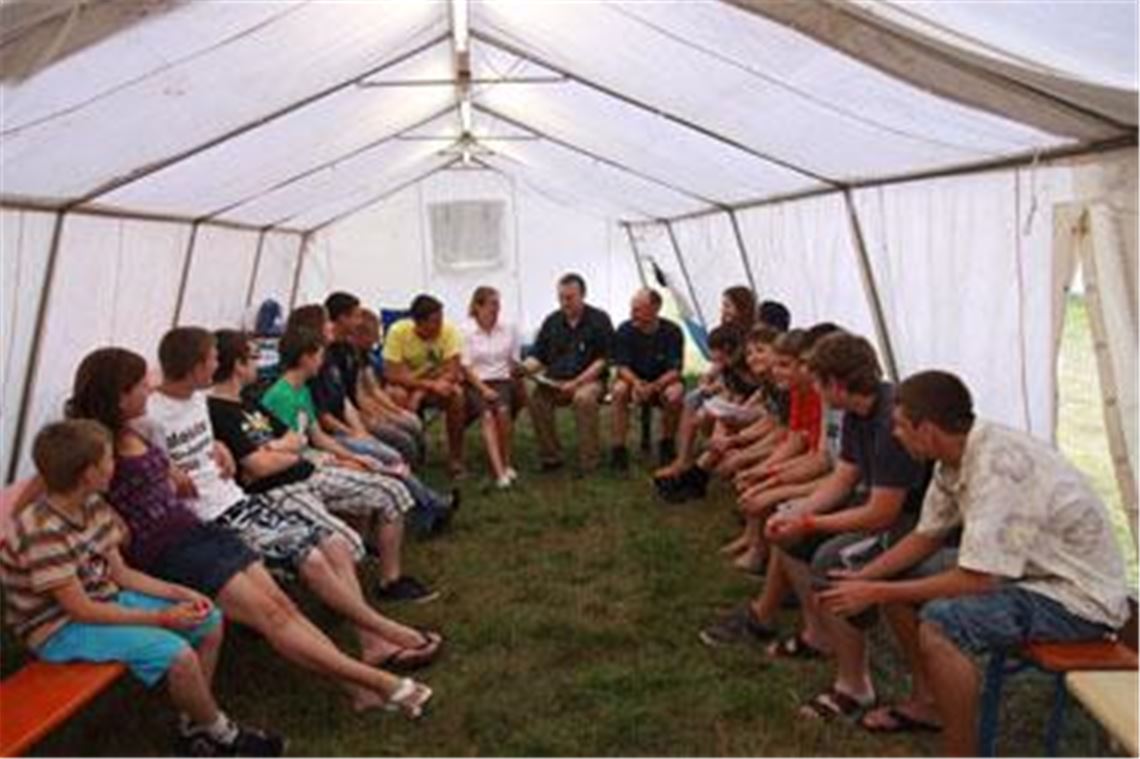 Wie entsteht eine aktuelle Tageszeitung ? Redakteur Gerhard Franz (Mitte), mit Kommandant Klaus Riekert und Bürgermeisterin Sigrid Hornauer, diskutiert im Zeltlager der Feuerwehrjugend mit jungen Teilnehmern. Dabei geht es auch um die wichtige Zusammenarbeit von Presse und Feuerwehr. Foto: privat