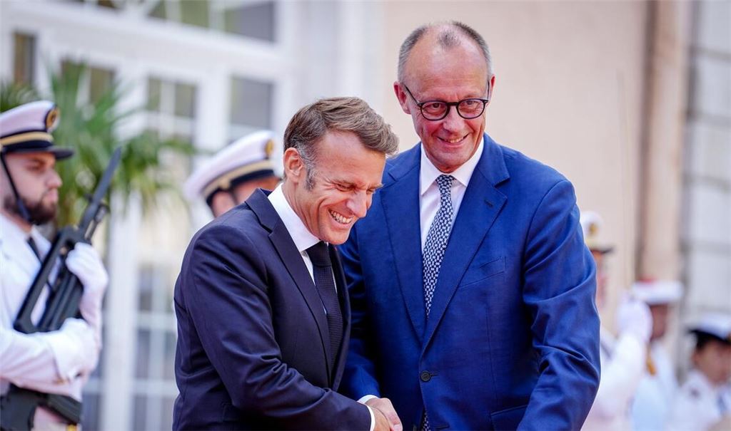 Wie zwei alte Freunde begrüßen sich Macron und Merz vor dem Fort du Cap Brun über der Cote d'Azur.
