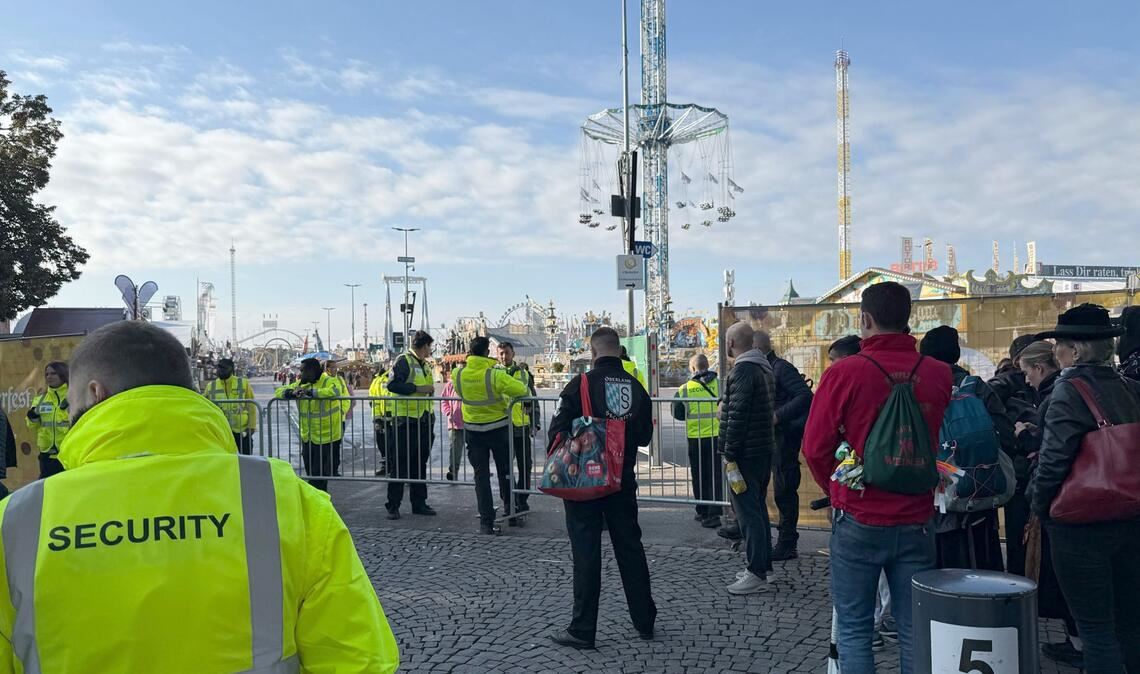 Wiesn-Besucher warten am Mittwochmorgen vor dem abgesperrten Festgelände.